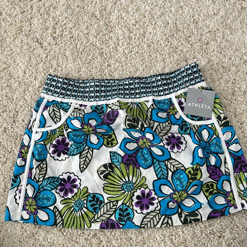 Athleta skirt with island print, white piping pockets & snap back pocket Size L